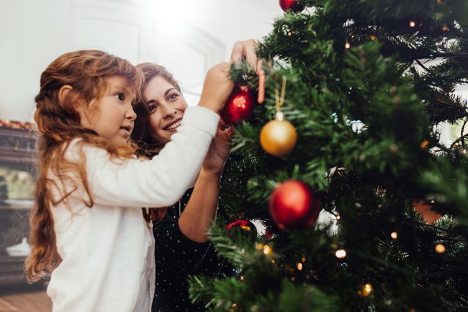 Mother and daughter celebrating Christmas and decorating tree