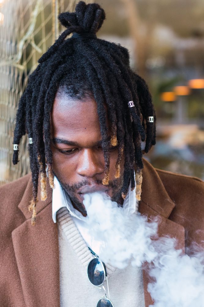 Hipster Black man with electronic cigarette on the street