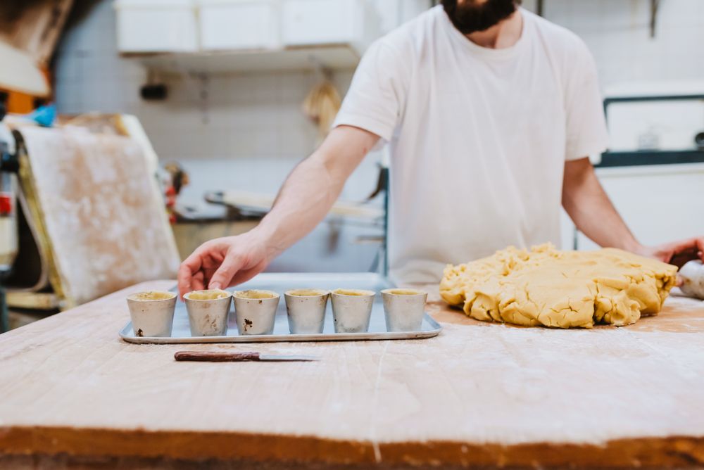 Bearded confectioner putting dough into cup