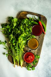 Top view of three traditional Georgian sauces tomato satsebeli, yellow and red tkemali with ingredients on cutting board