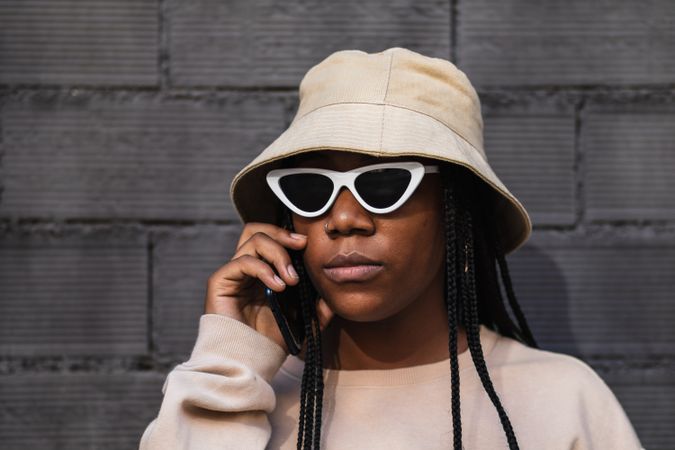 Black woman talking on smartphone near brick wall