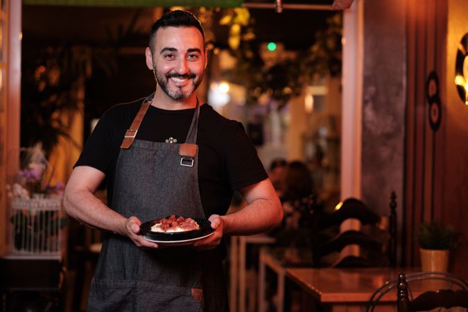 Cheerful waiter serving snack in restaurant