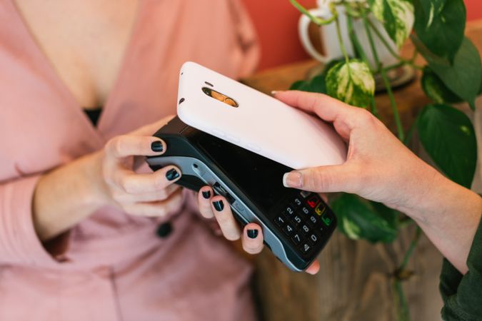 Anonymous woman paying for skin care treatment with smartphone on POS terminal