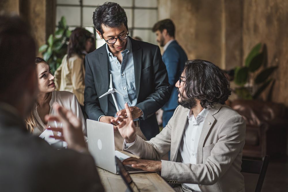 Businesspeople talking together around the desk with wind turbine models