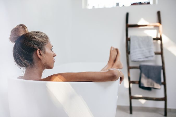 Shot of young woman lying in bathtub and looking away