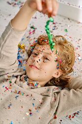 Boy covered with confetti lying on floor