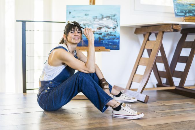 Portrait of a woman artist siting on the floor while looking at camera.