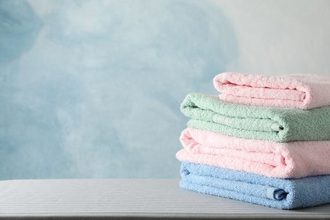 Stack of clean towels on ironing board, copy space