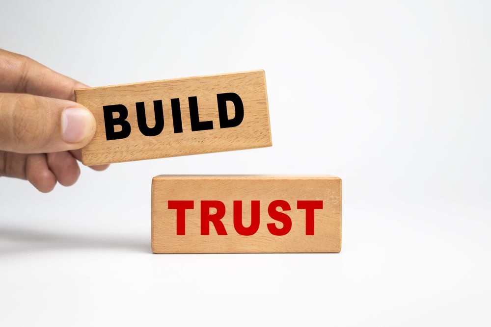 male hand putting wooden blocks with build trust words