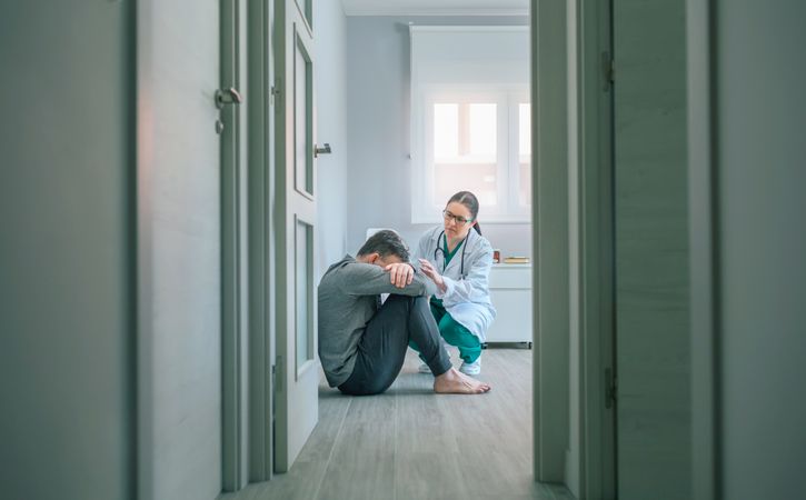 Psychiatrist talking to patient sitting on room floor