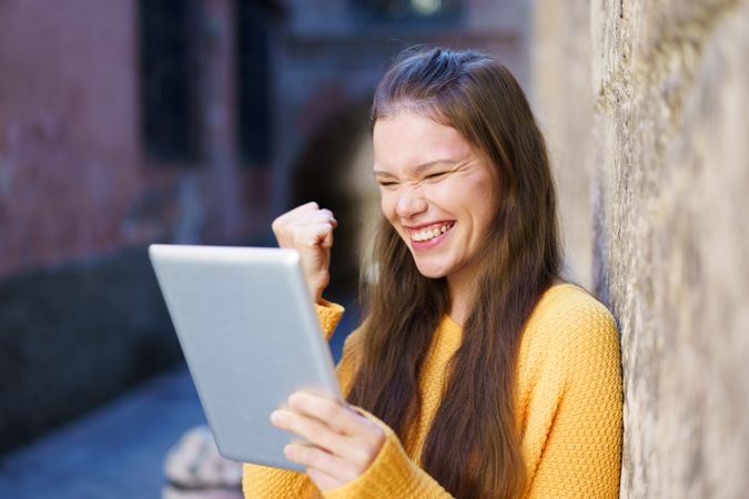 Joyful Young Woman Celebrating on a Tablet in a Beautiful Historic Urban Setting Today