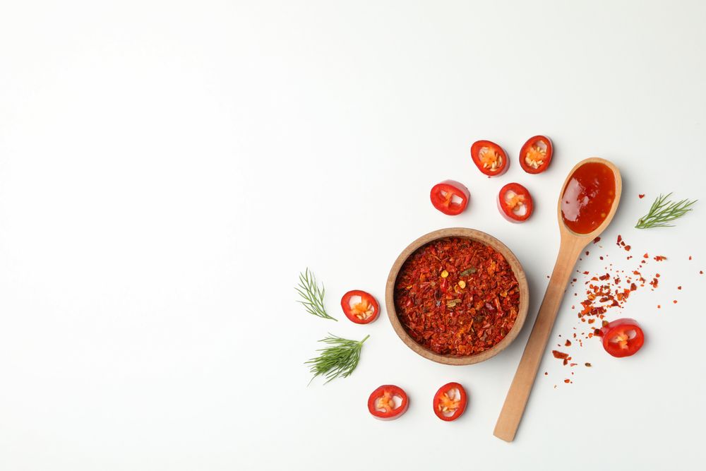 Composition with chilli pepper, spice and sauce on studio background