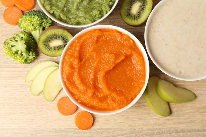 Bowls with vegetable puree on wooden background. Baby food