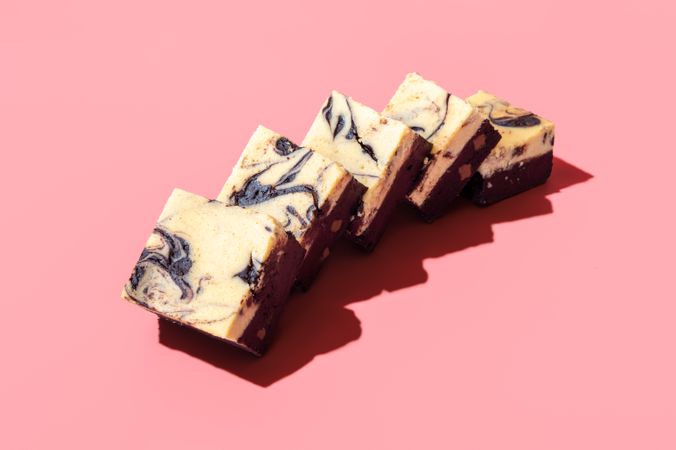 Cheesecake brownie slices isolated on a pink background