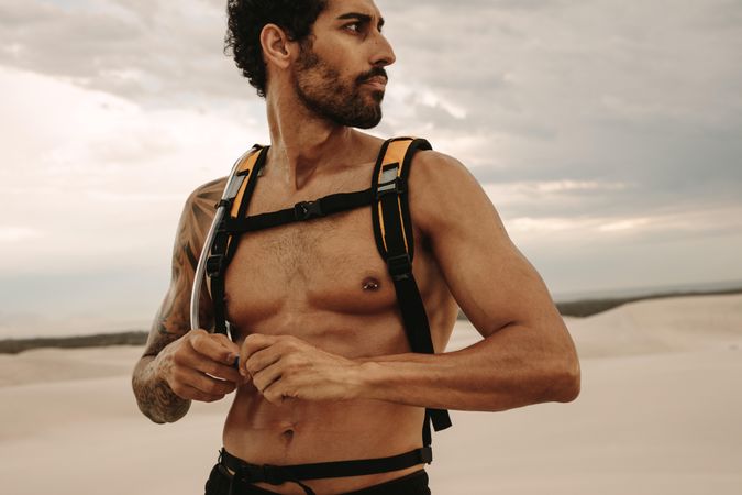 Fit man with hydration pack taking rest after outdoor workout