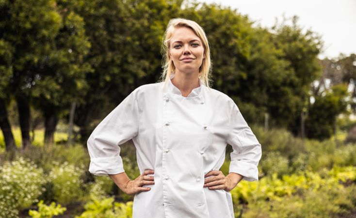Confident female chef standing with her arms on her hips on an organic farm