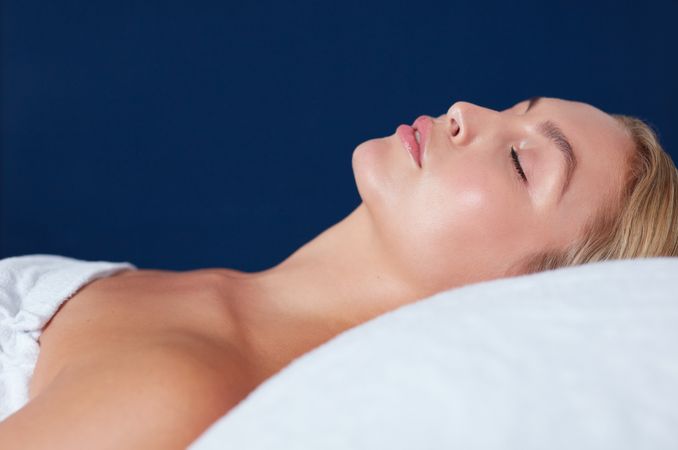 Blonde woman lying back with eyes closed for beauty treatment with copy space