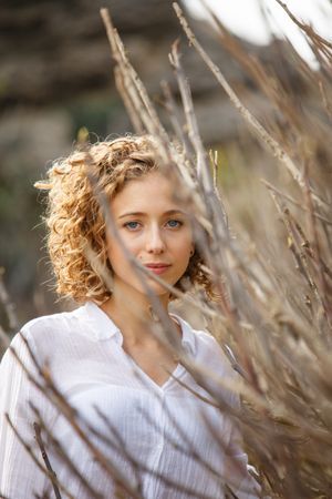 Young woman near dry twigs of bushes