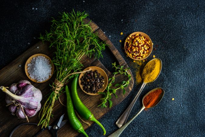 Cooking concept with pepper, herbs, oil and seasoning on cutting board