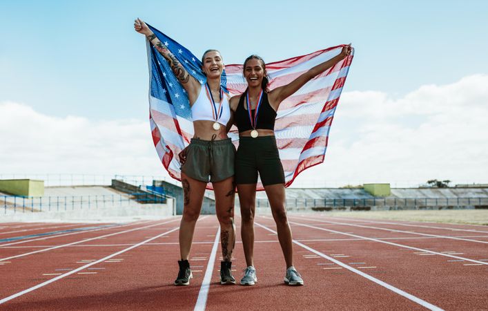 Winning athletes holding the US flag behind at stadium