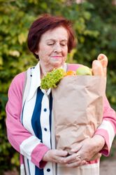 Older woman holding grocery bag standing outdoor