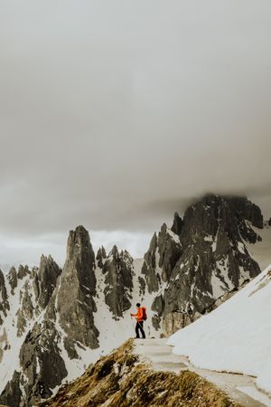 Person with backpack standing on snow covered ground near snow covered mountain