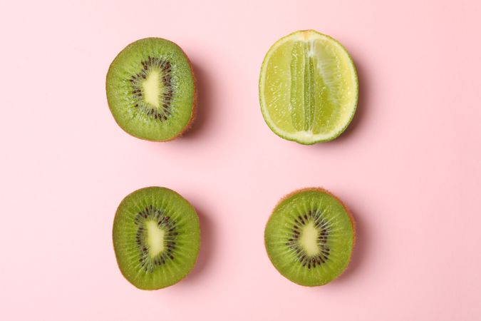 Lime and avocado on pink background, space for text