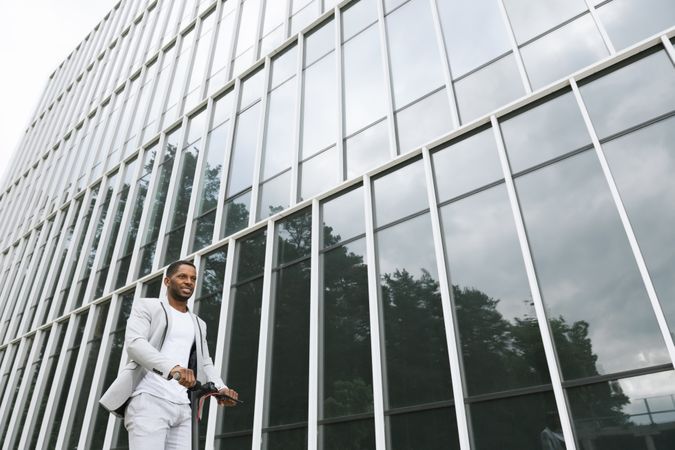 Black man in suit on electric scooter in business center