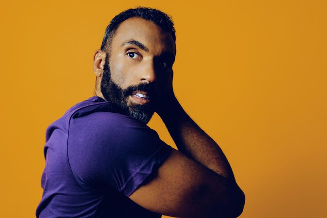 Confident Black man in yellow studio resting head on his hand