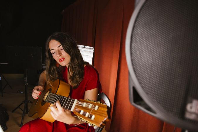 Creative woman singing and playing guitar on stage