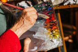 Crop artist with paint palette in workshop