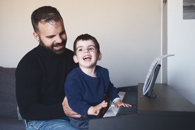 Father teaching son to play piano