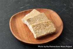 Slices of fresh tempeh on wooden plate bGawY5