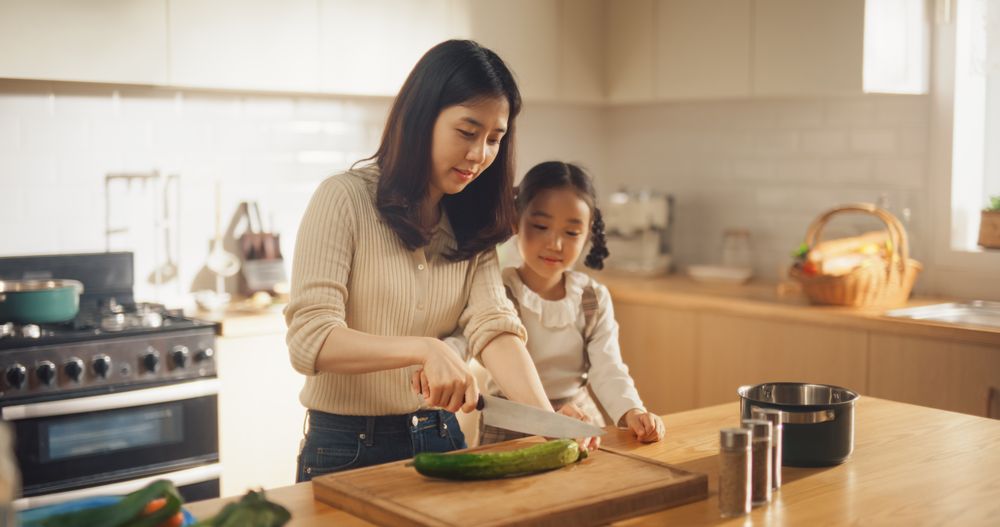 Mother and Female Child Spending Time Together, Learning how to Use a Kitchen Knife Safely
