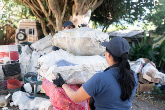 An Adult Hispanic Woman is Stacking recycled glass bottle Sacs