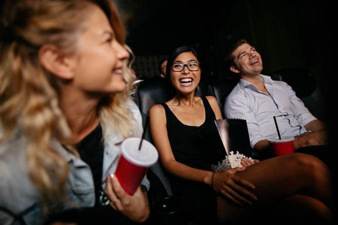 Young woman with friends watching movie in cinema