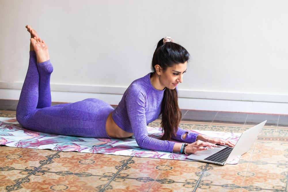 Woman using laptop during yoga training at home