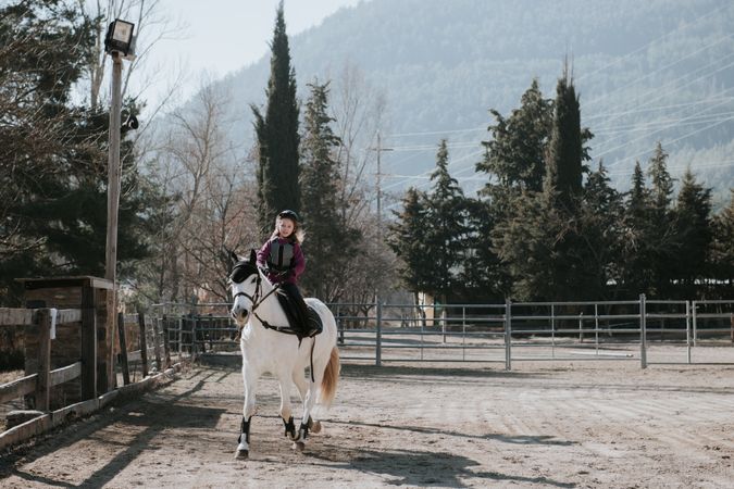 Little girl riding horse in enclosure