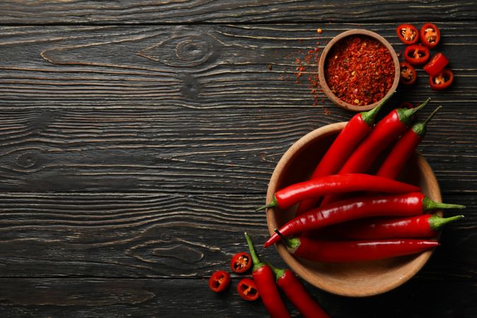 Spices and bowl with chilli pepper on wooden background