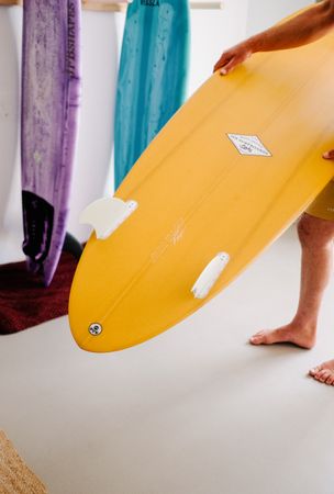 Man choosing surfboard at home before heading to the beach