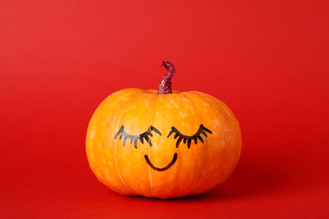 Pumpkin with smile on red background, space for text