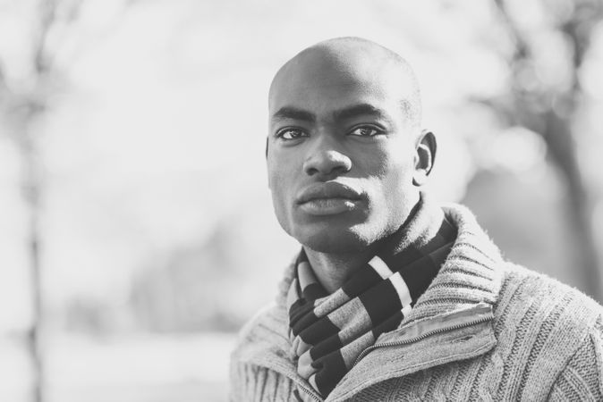 B&W picture of serious male in sweater standing in park