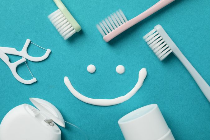 Smile and dental care tools on turquoise background, top view