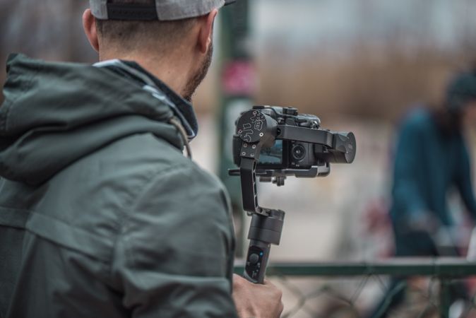 Back view of man holding a video camera with stabilizer