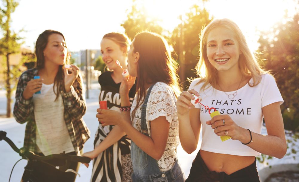 Group of female friends blowing bubbles in the sun