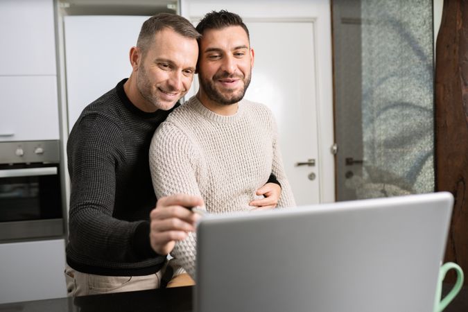 Male couple looking at laptop screen together