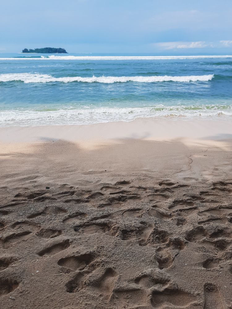 Footprints on sandy beach near ocean waves in Angso Duo Island, Pariaman, Indonesia