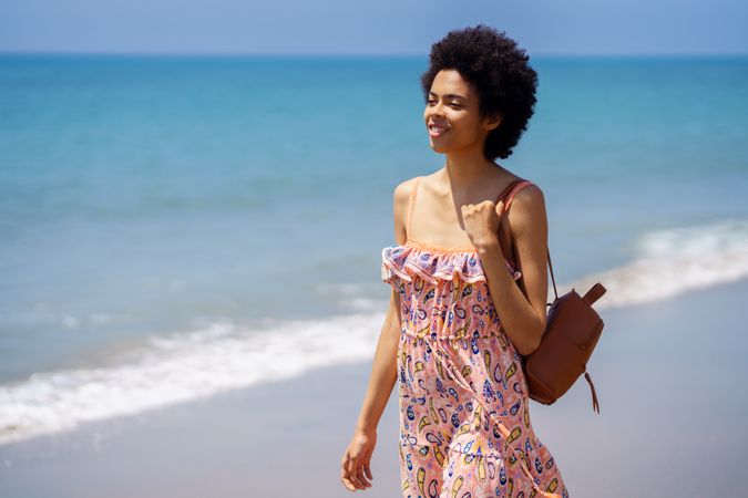 Smiling female in maxi dress walking along the coast