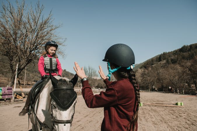 Young woman teaching girl to ride horse