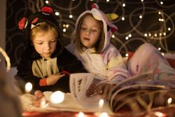 Kids reading Christmas fairy tales in bed